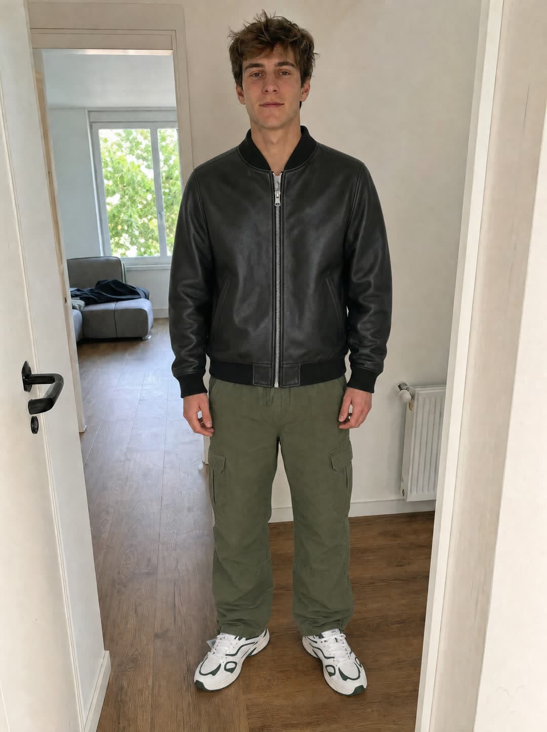 The same person in a leather bomber, olive cargo trousers and retro sneakers